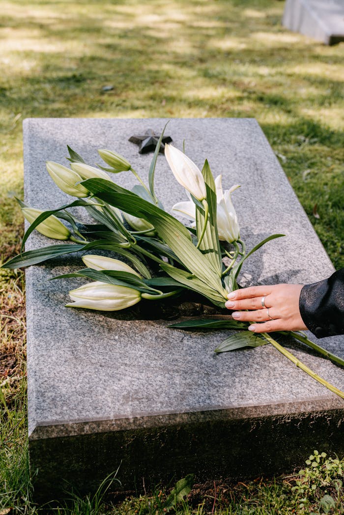 White lilies on a gravestone symbolize remembrance in an outdoor cemetery setting.